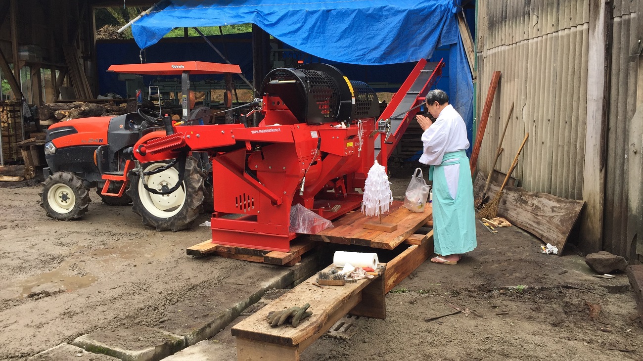 A Japanese priest giving their blessings to a firewood processor.